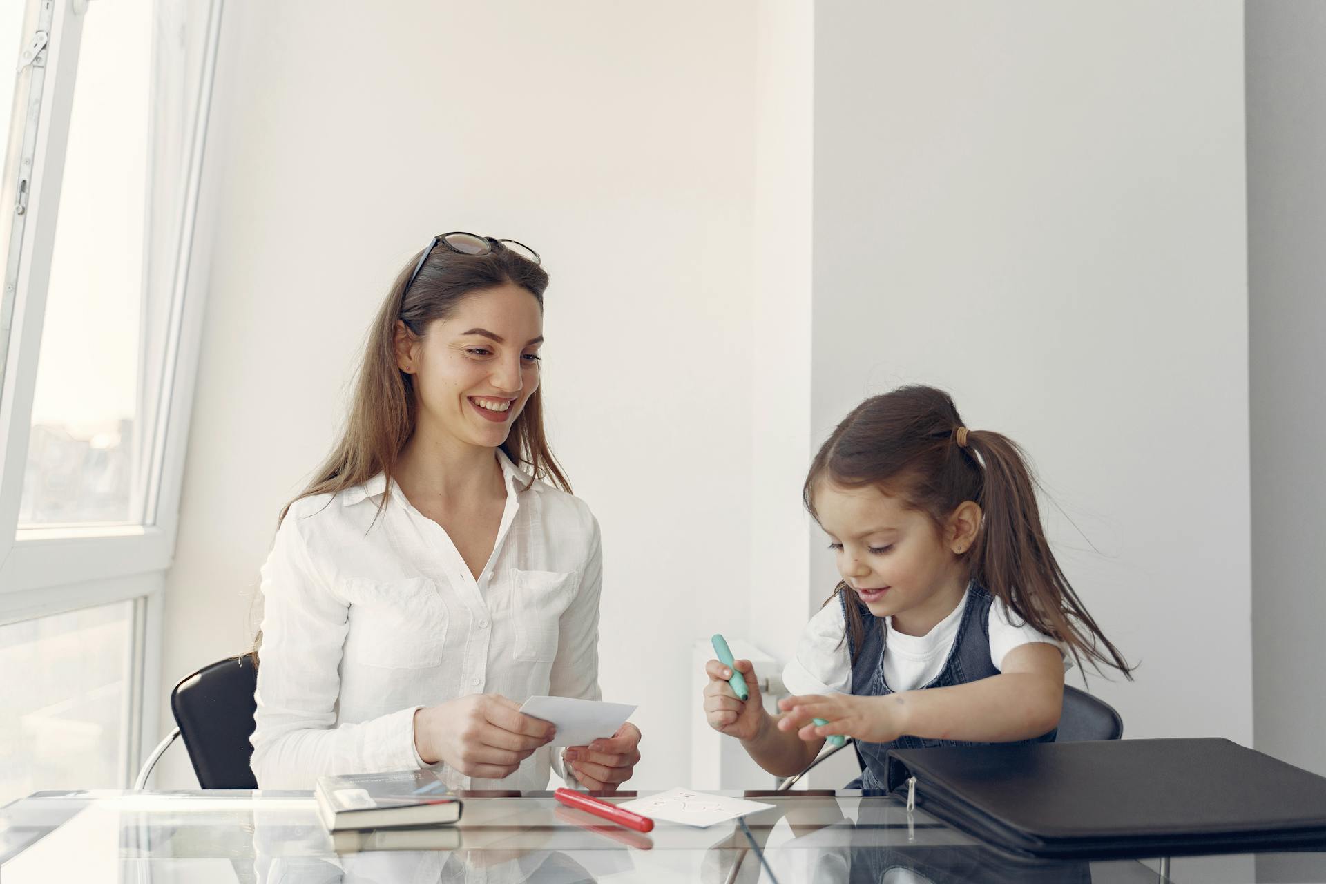 Woman and child engaged in creative activity at a table, with papers and art supplies, promoting companionship and nurturing relationships in home care settings.